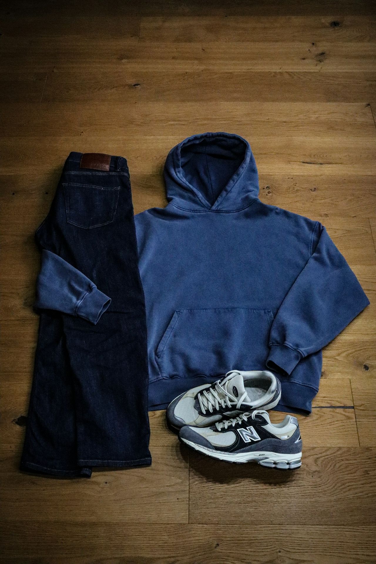 A pair of jeans and a hoodie on a wooden floor